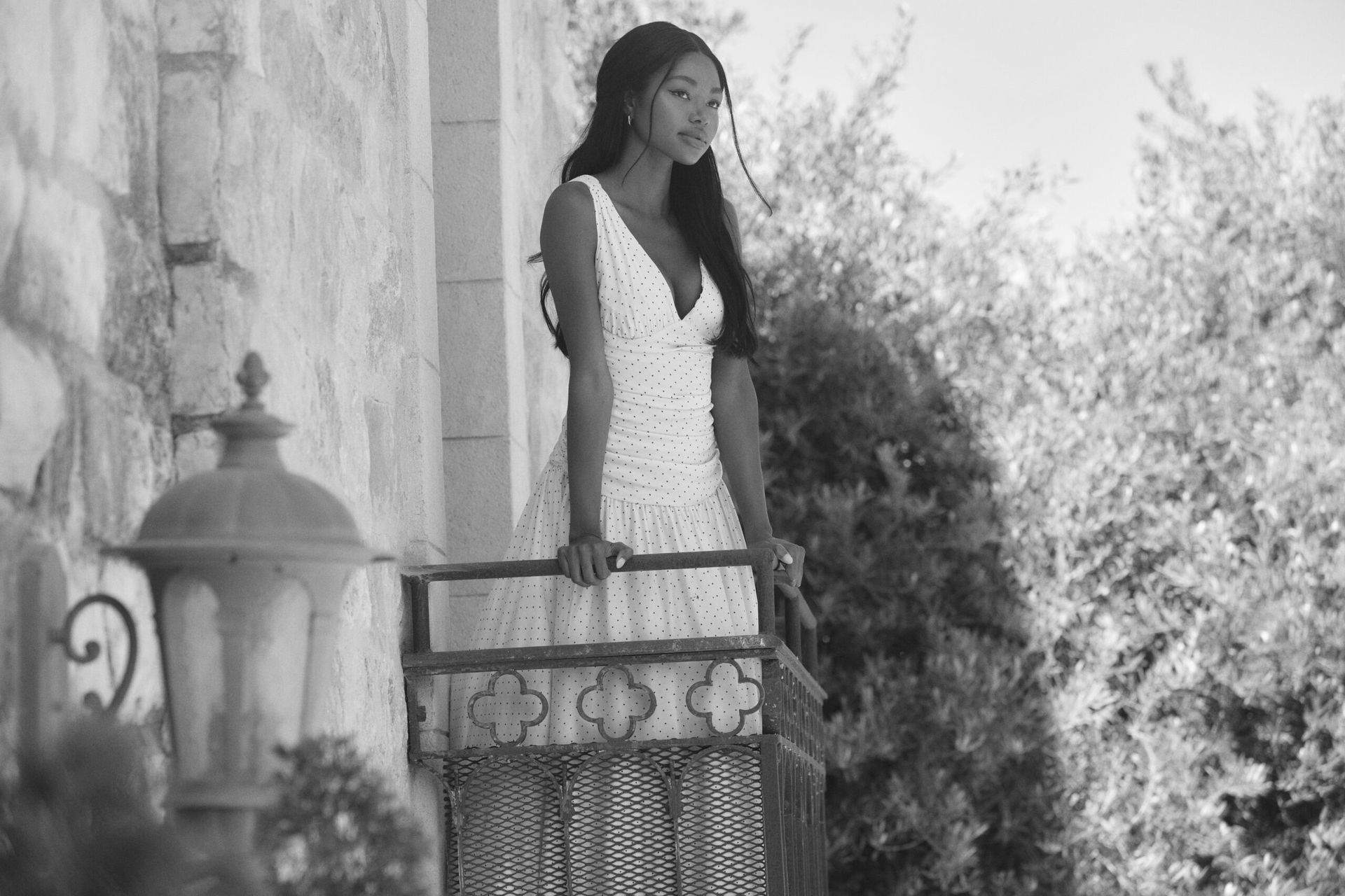 model on balcony wearing white dress
