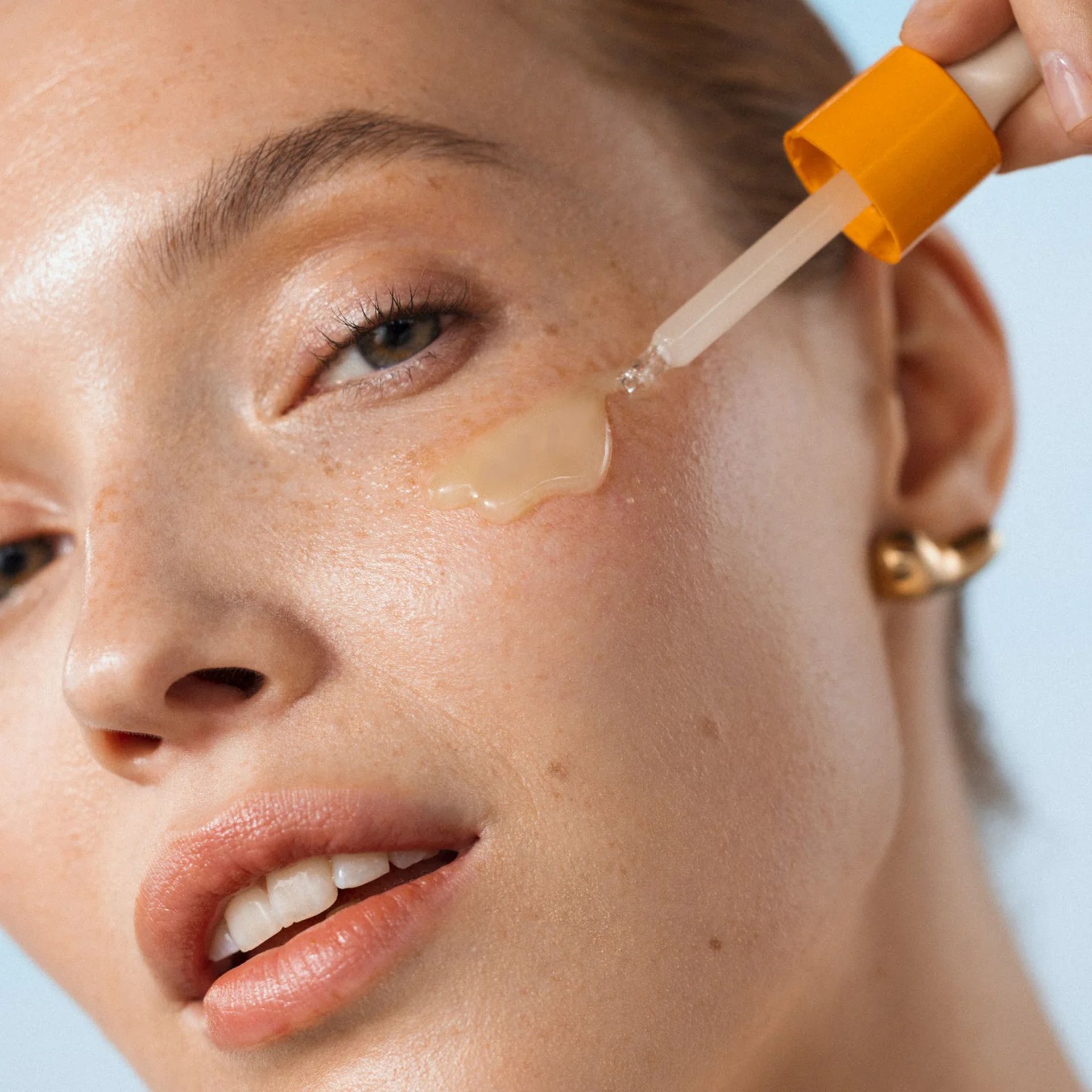 close up of model putting serum on face
