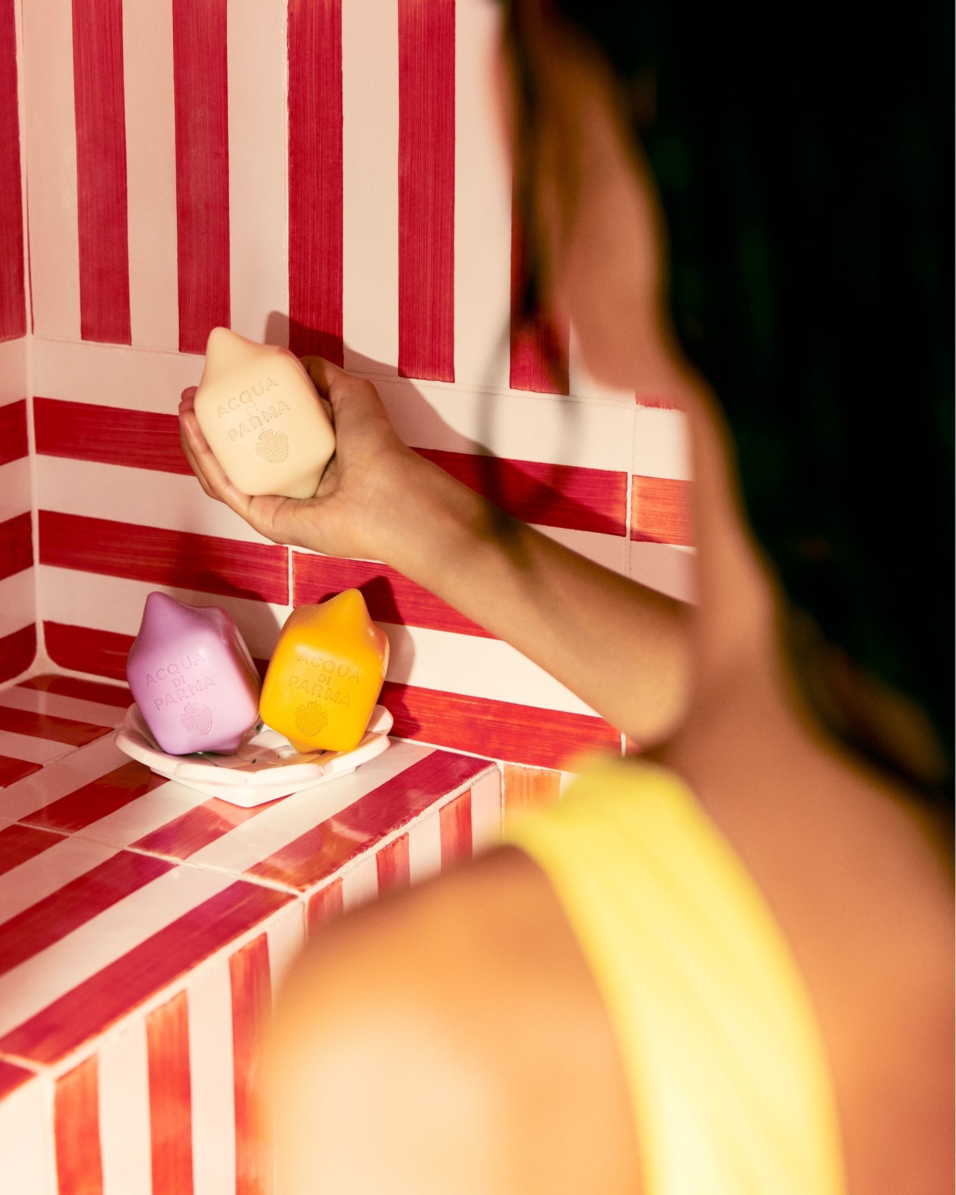 model from back holding soap in striped tiled shower