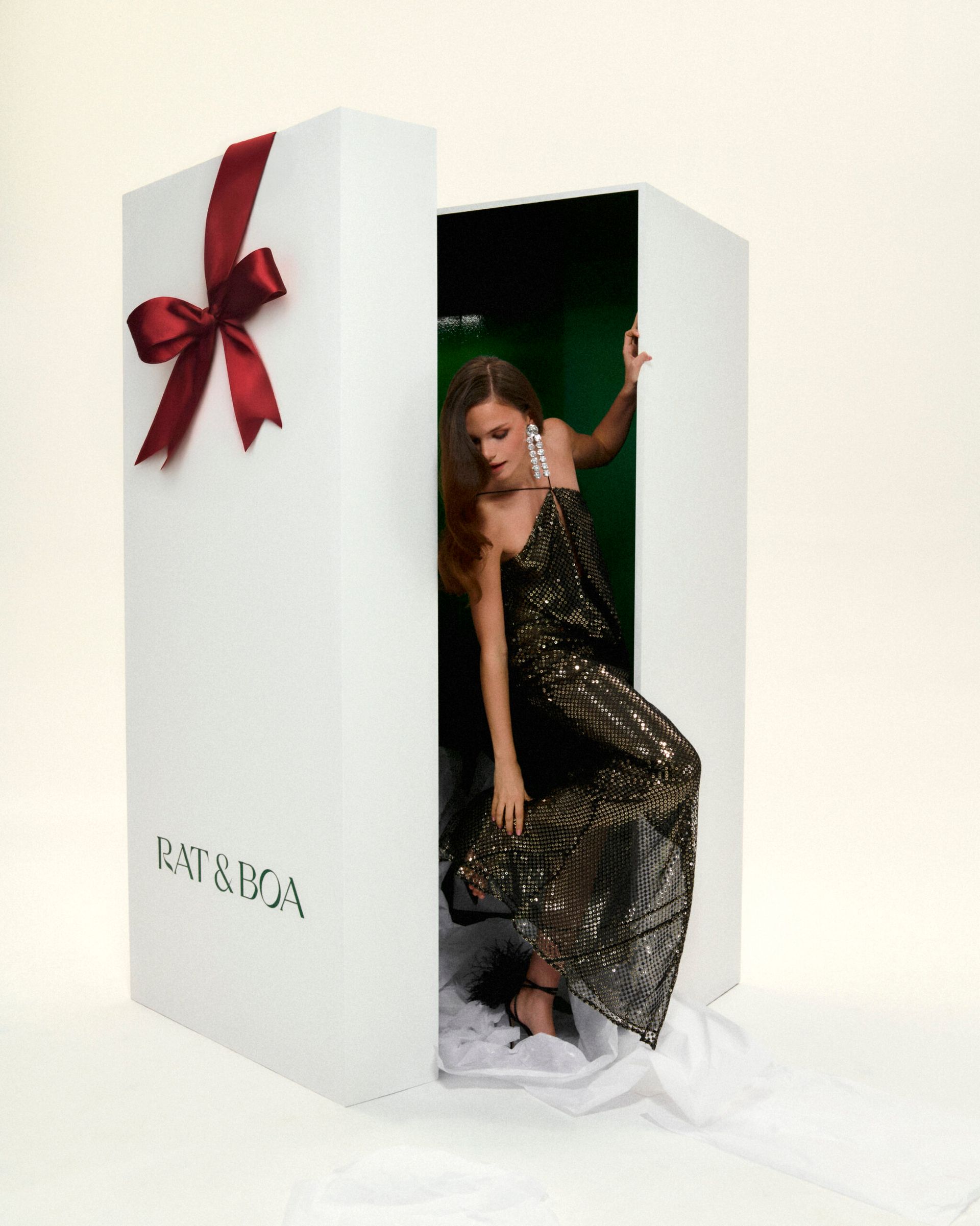 model in black gown coming out of present box