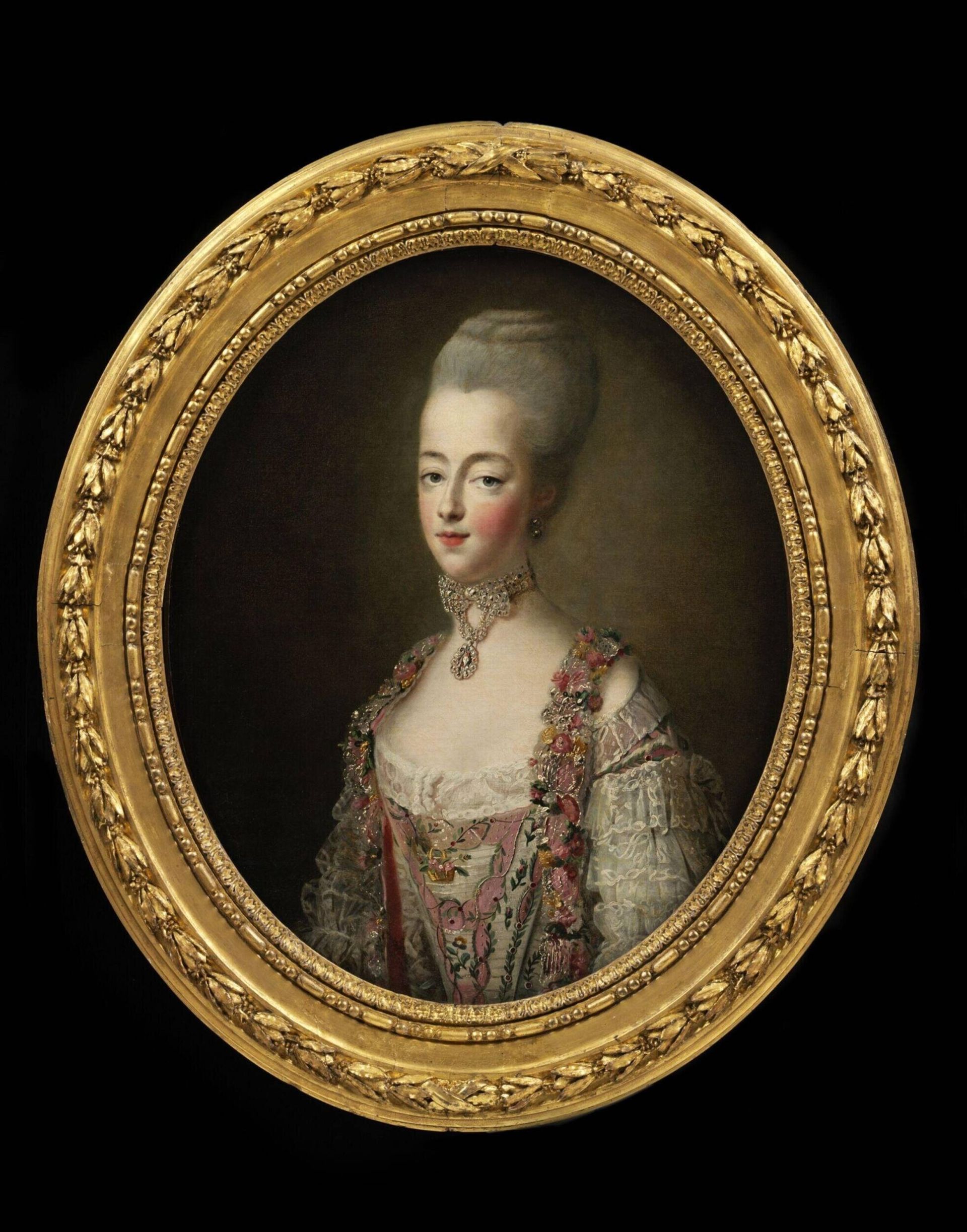 Oval portrait of an 18th-century woman with pale skin and tall white hair, wearing an ornate dress with lace and floral details—her style reminiscent of looks featured in grand Fashion Exhibitions—adorned by pearls and a jewelled pendant, in a gold frame.