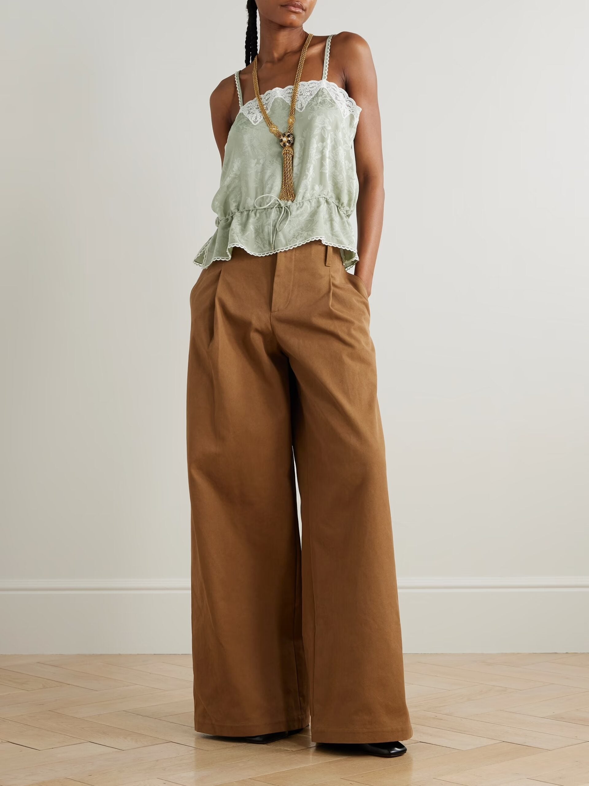 model wearing pale green lace cami and brown trousers 