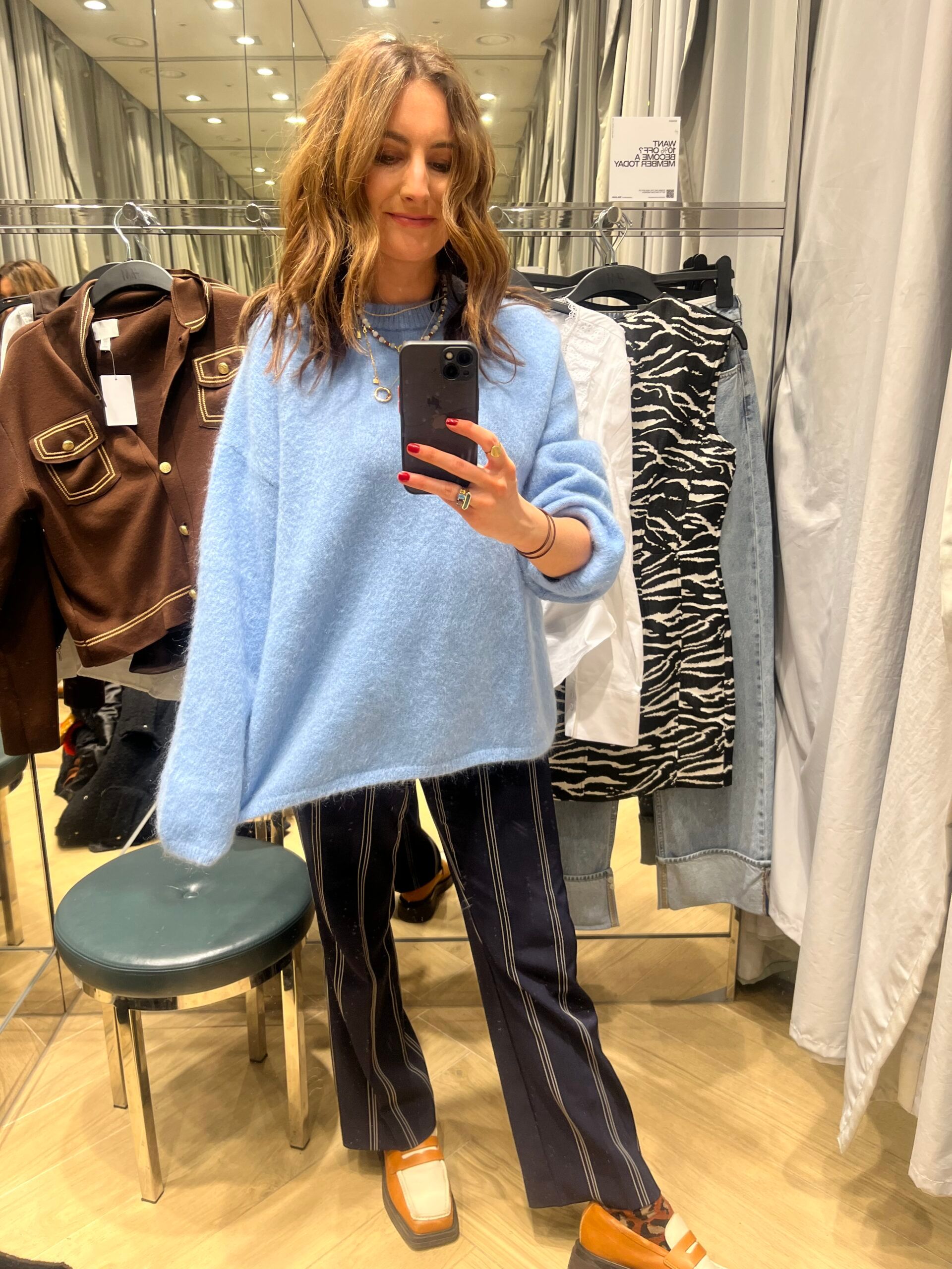 Astrid in changing room wearing smart trousers and blue jumper