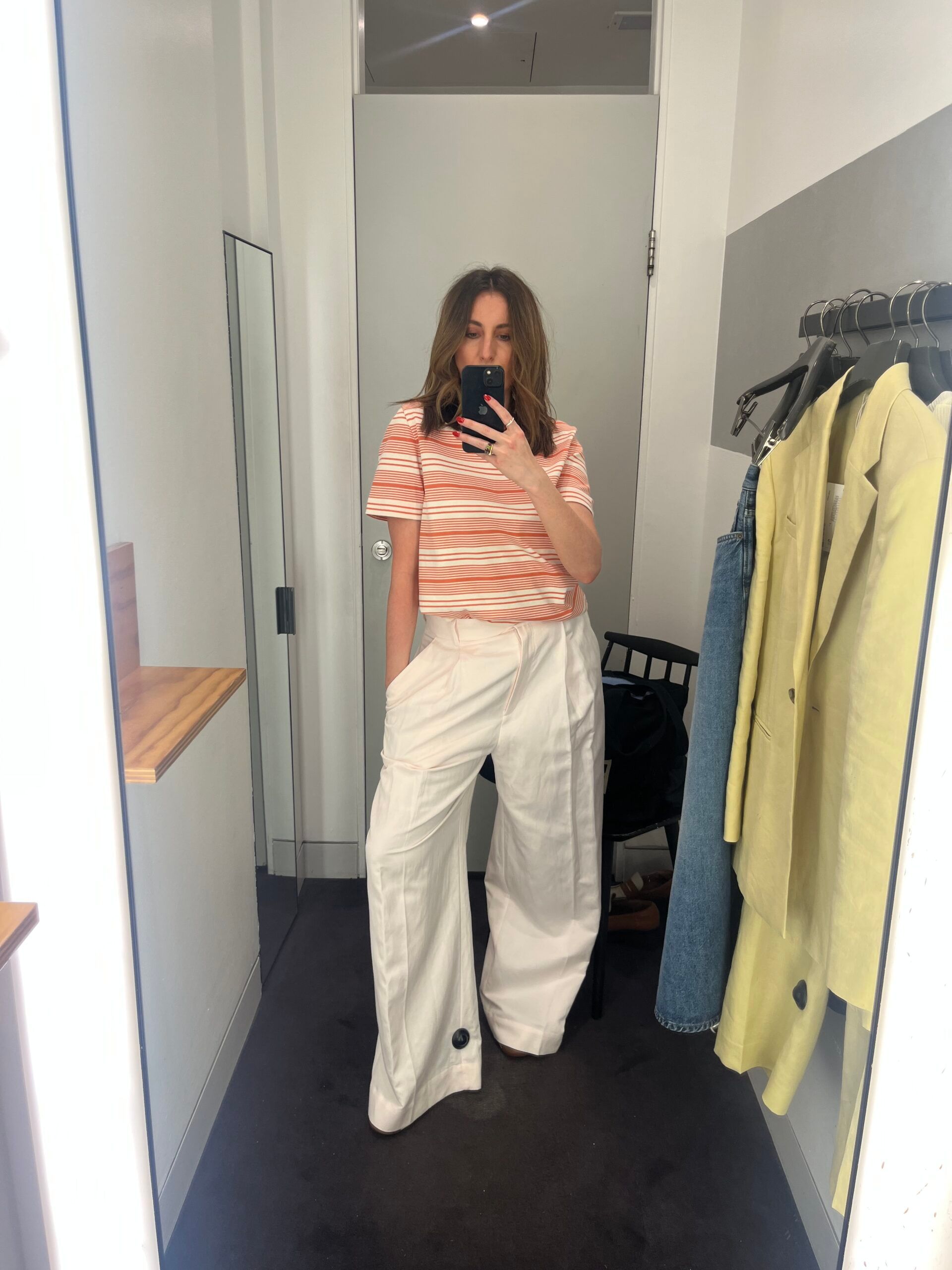 Astrid in changing room wearing smart trousers and striped tee