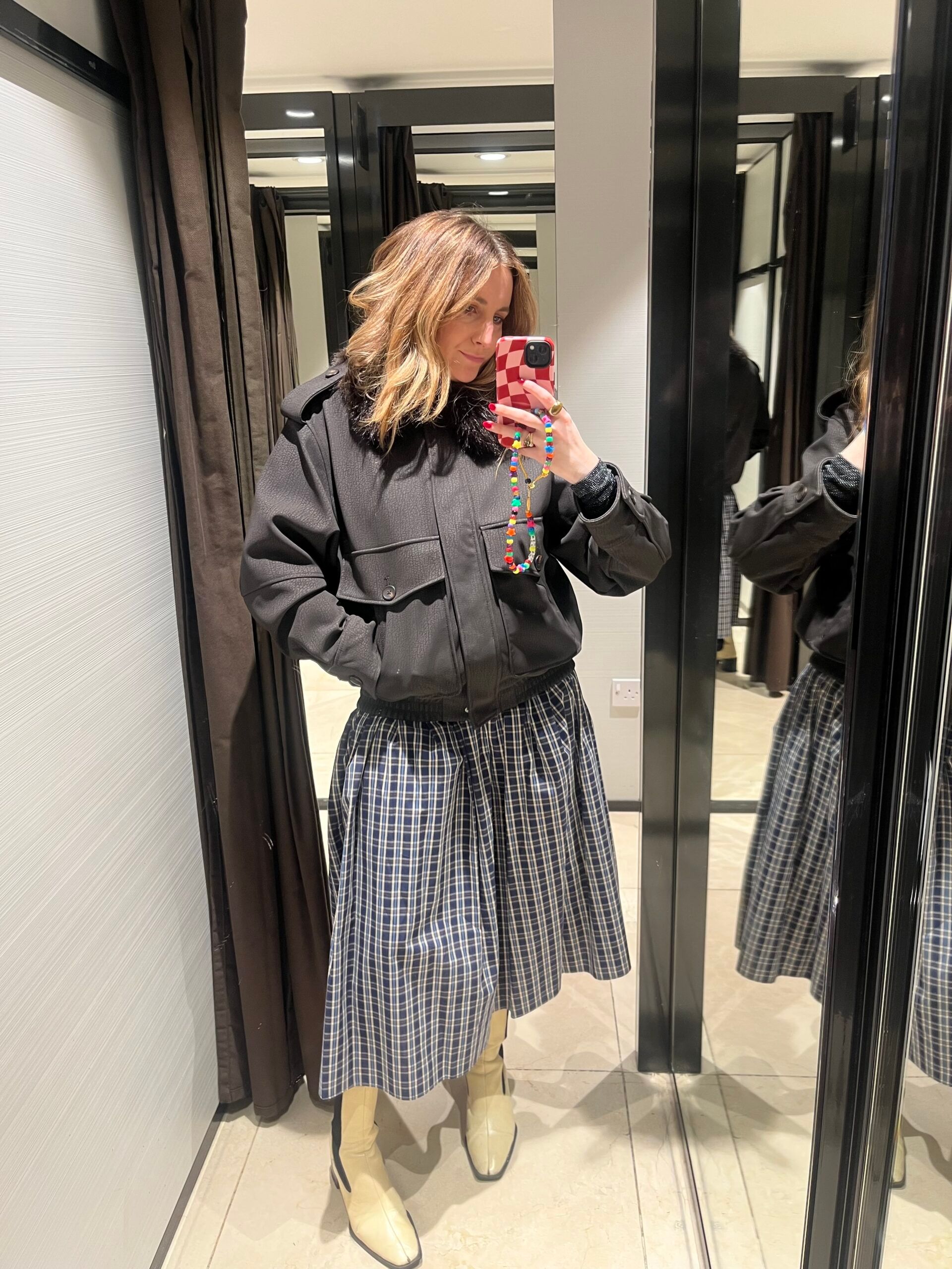 astrid in zara changing room wearing suede brown jacket and check skirt