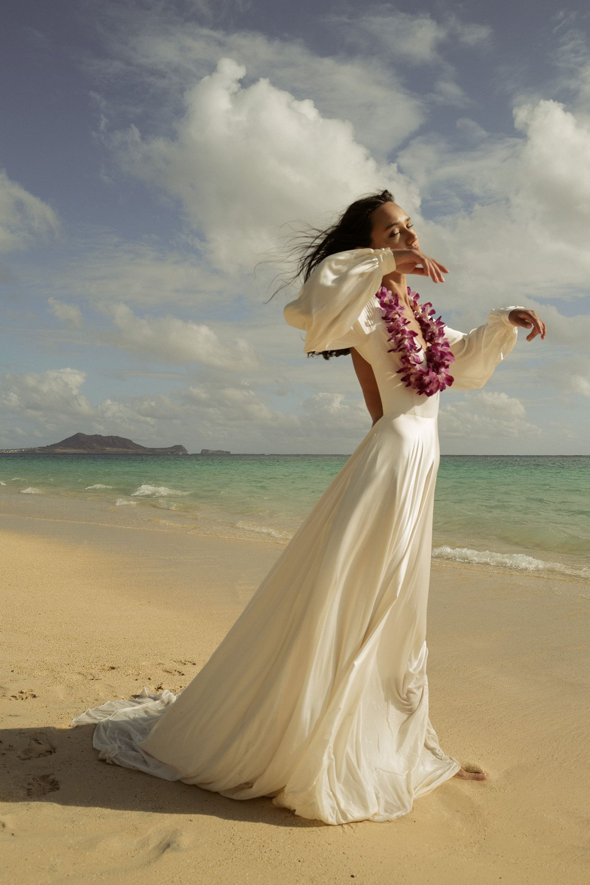 model on beach wearing wedding dress 
