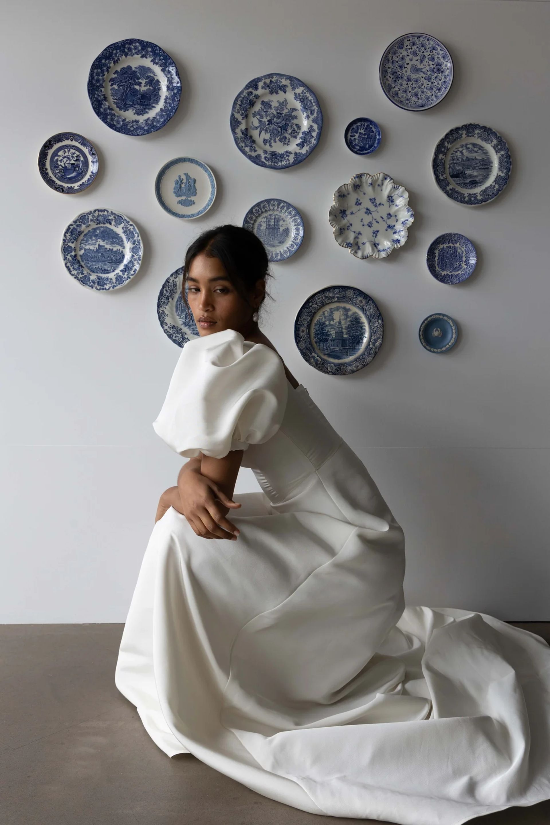 model crouching wearing white puff sleeve wedding dress 