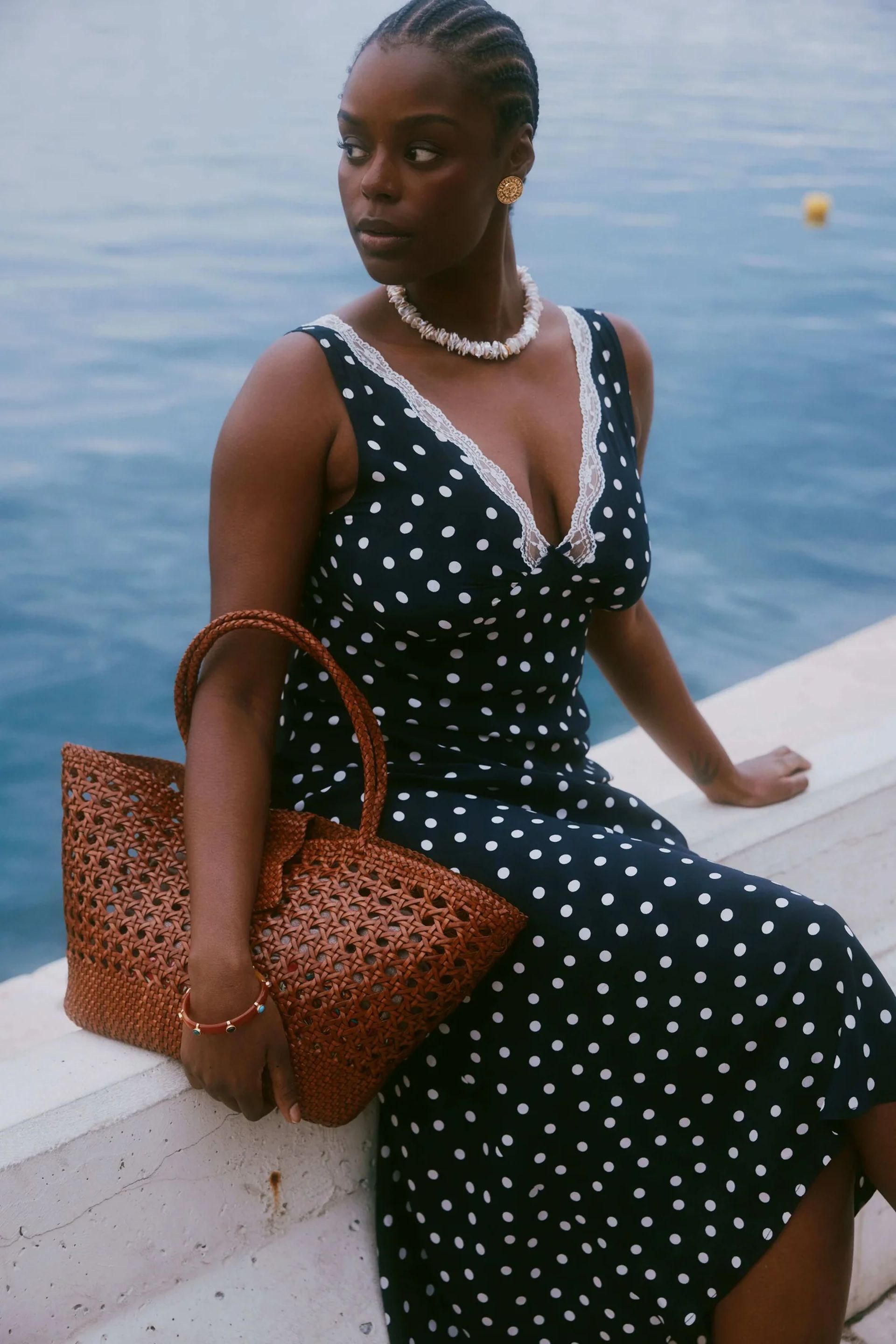 model sitting by water with rixo basket bag