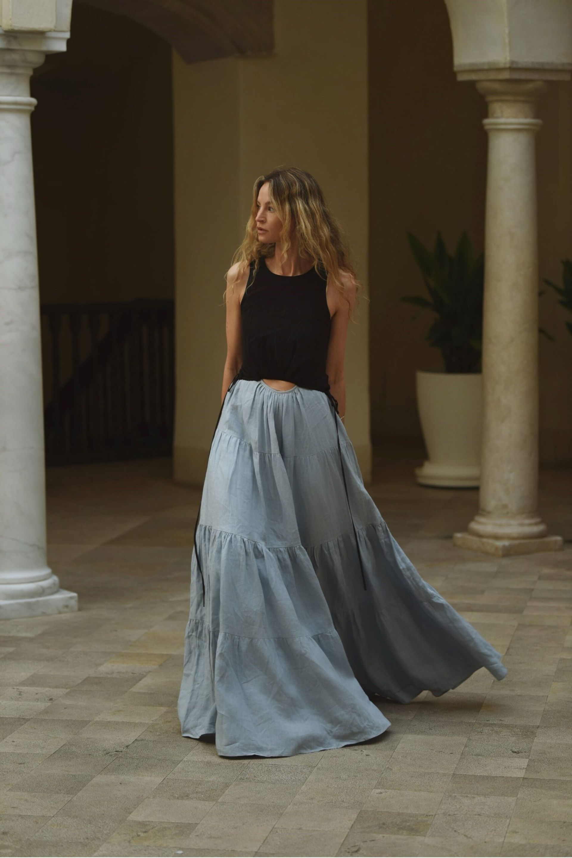 yve wearing black vest and blue maxi skirt