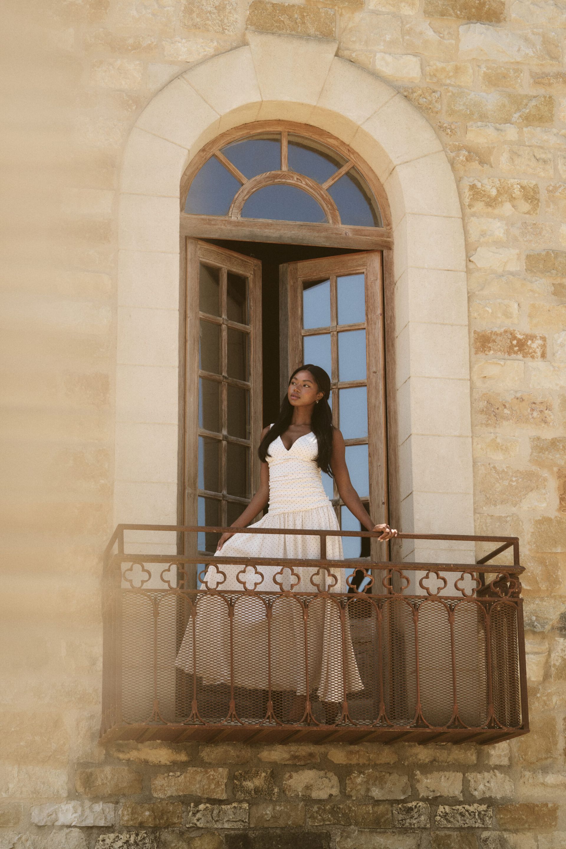 model on balcony wearing white dress