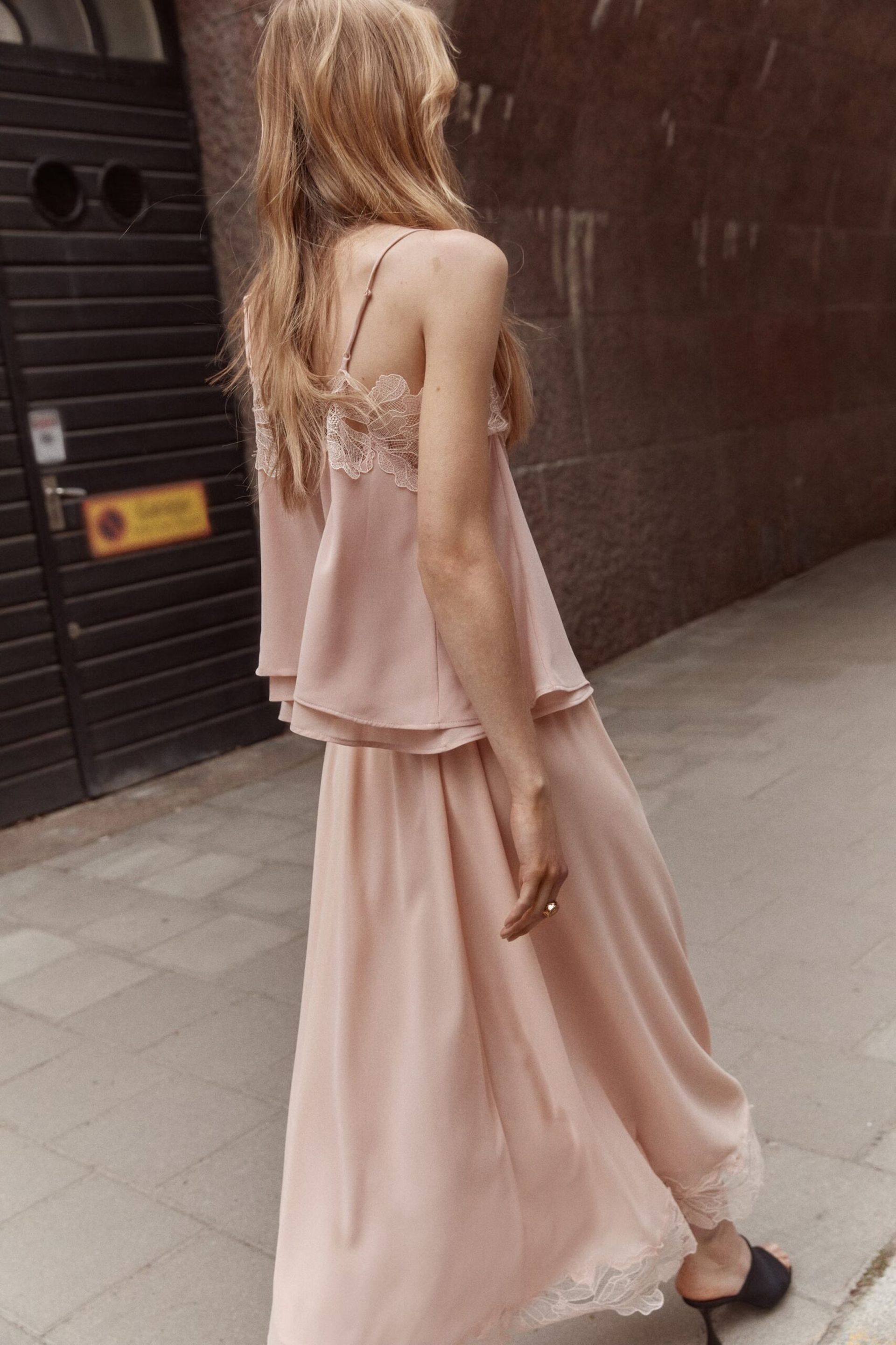 model wearing pink lace trim skirt and top walking in street