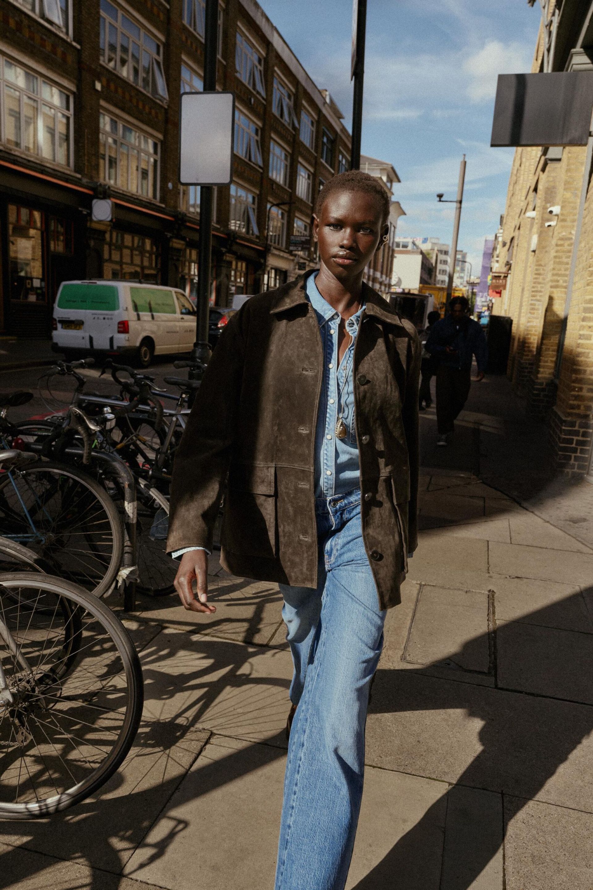 model walking down street wearing suede jacket and jeans