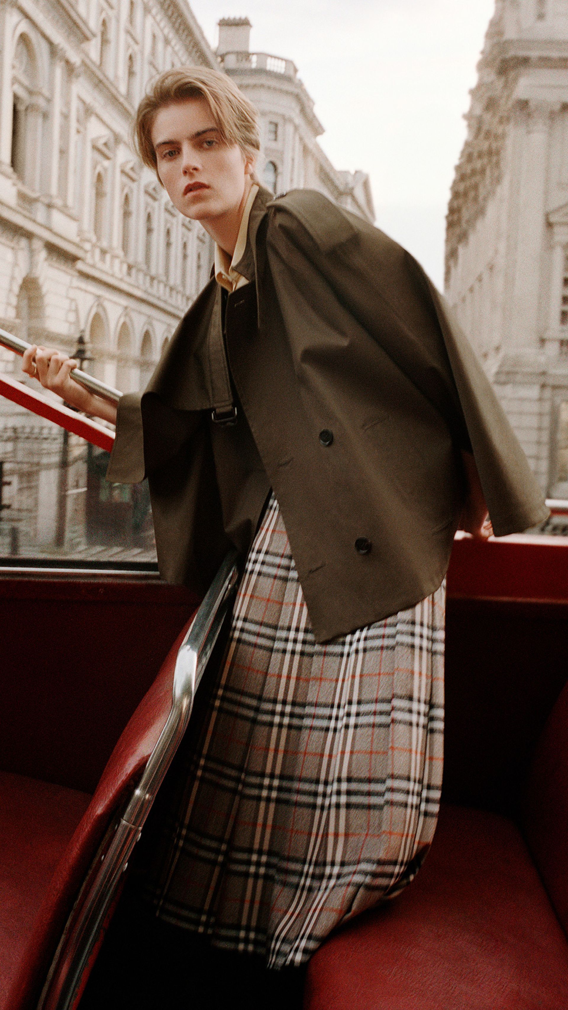 model on top deck of london bus wearing burberry trench and check skirt 