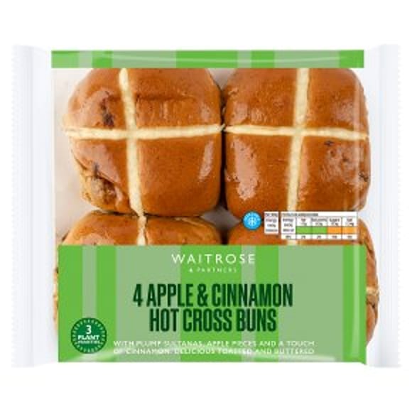 Four glazed apple and cinnamon hot cross buns in a clear plastic Waitrose pack, each bun marked with a white cross, labelled “4 Apple & Cinnamon Hot Cross Buns” on a green background—perfect for Easter entertaining.