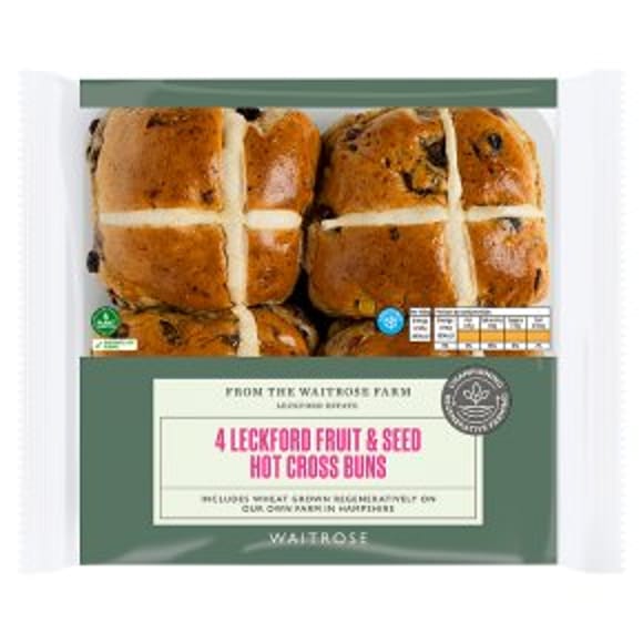A pack of four Leckford fruit and seed hot cross buns from Waitrose, in clear packaging with green and white labelling—perfect for Easter entertaining, each bun features the classic cross marking on top.
