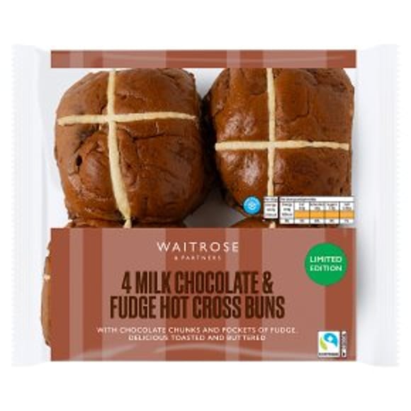 A pack of Waitrose 4 Milk Chocolate & Fudge Hot Cross Buns, perfect for Easter entertaining, with four buns topped with white crosses in a clear wrapper and a brown and green Limited Edition label.