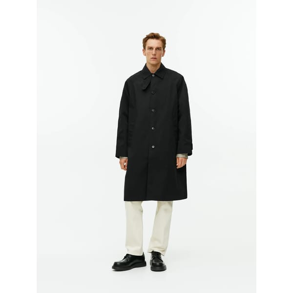 model wears black car coat and white jeans