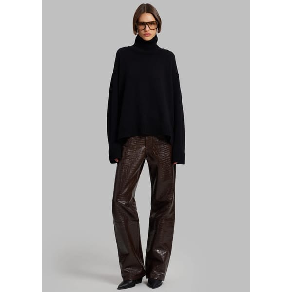 model wears brown croc effect trousers and black jumper
