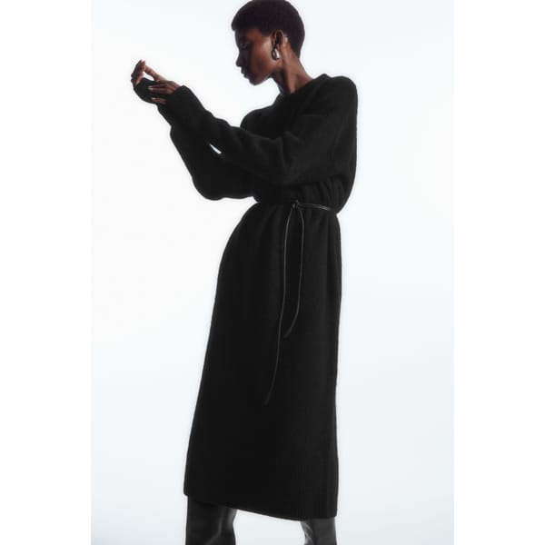 model wears black belted knitted dress