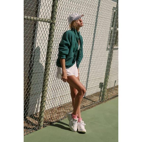 model on tennis court in green fleece jacket