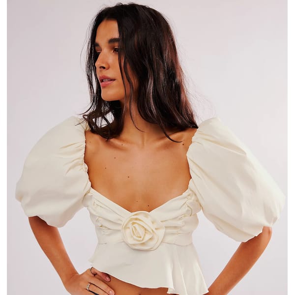 model wears white top with flower detail and puff sleeves