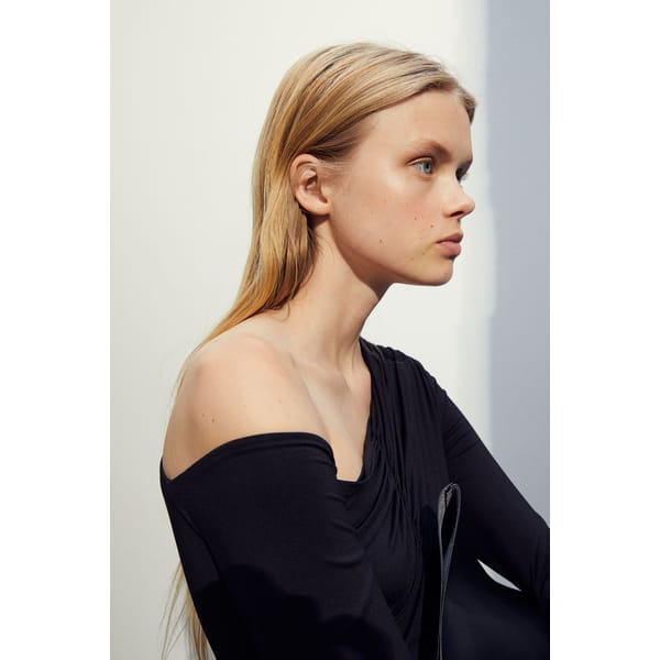 model in draped shoulder black top