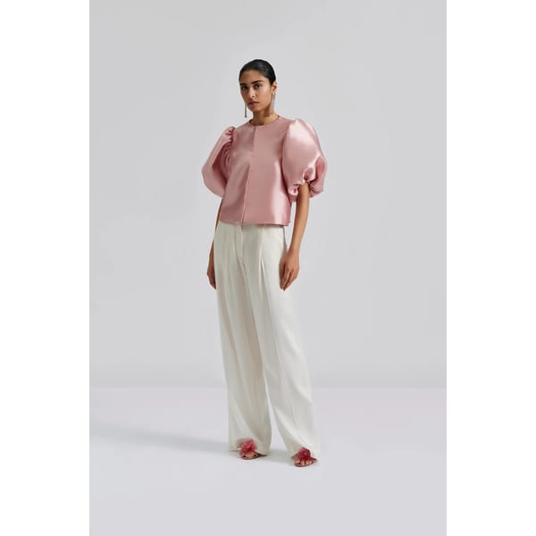 model wears pink puff sleeve top and white trousers