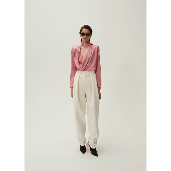 model wears pink blouse and white trousers