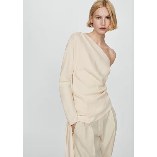 model wears one shoulder cream blouse