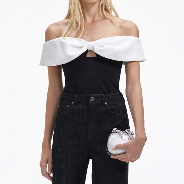 model wears black top with white bow detail