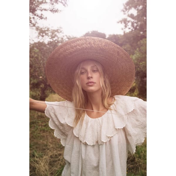 model in white prairie blouse and straw hat