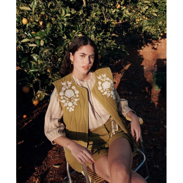 woman sitting in chair wearing mustard gilet