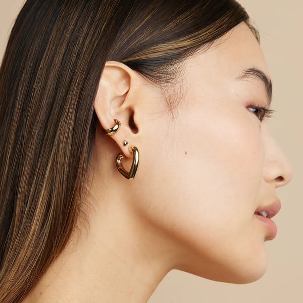 model wears ASTRID & MIYU HEART OPEN HOOPS IN GOLD