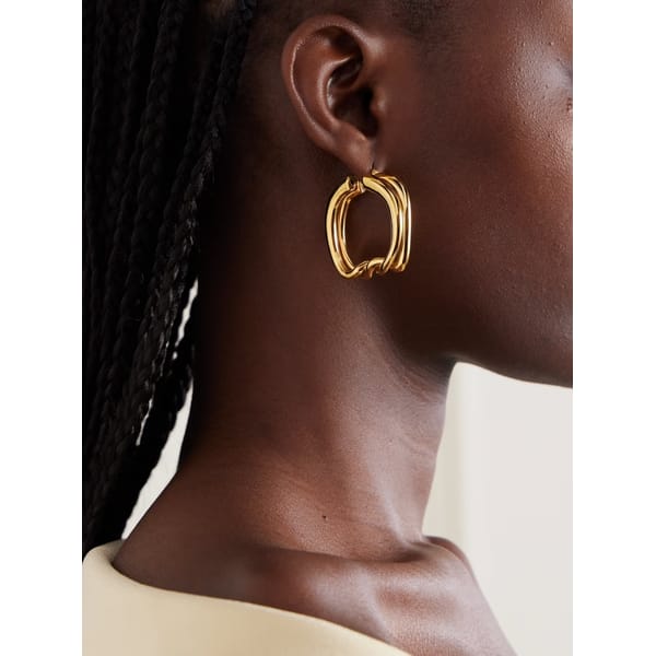 model close up wearing JACQUEMUS Nodi gold-tone hoop earrings