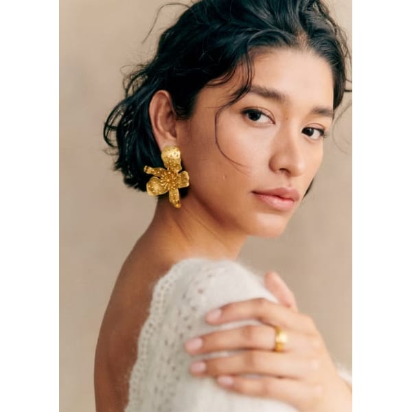 model wearing gold flower earrings