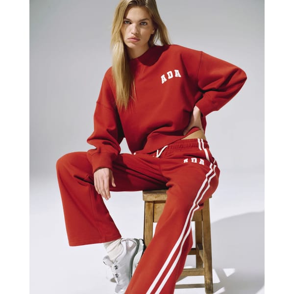 model sitting in red and white tracksuit