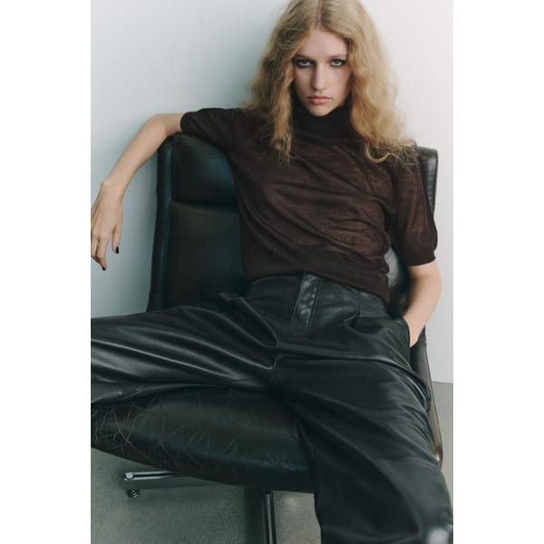 model sitting wearing CASHMERE AND SILK HIGH NECK SWEATER