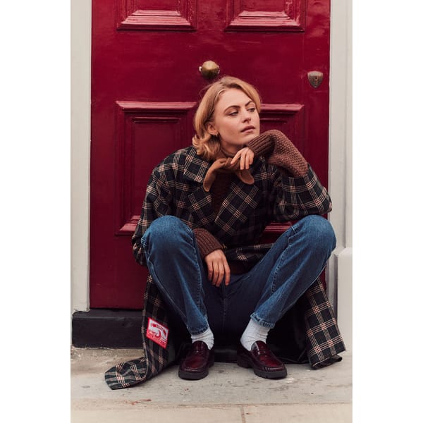 model sitting in doorway wearing tartan coat