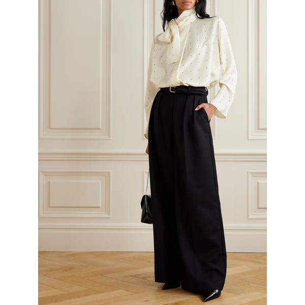 model wears cream polka dot blouse and black trousers