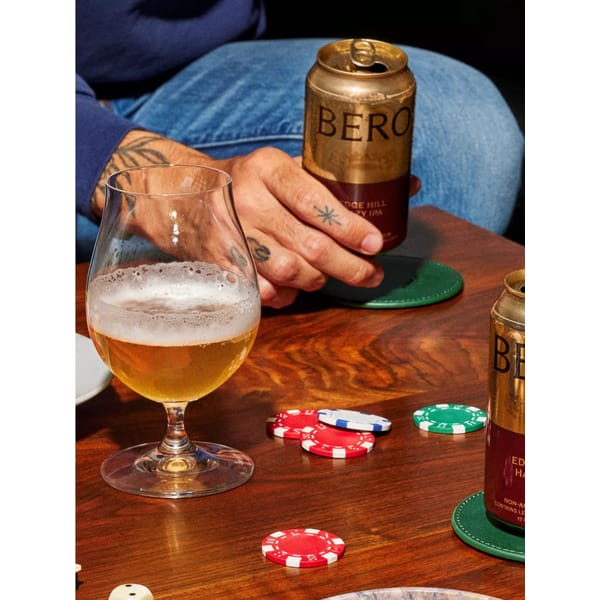hand bolding beer on poker table