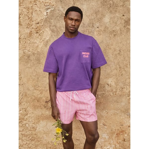 male model wearing purple t-shirt and pink swim shorts