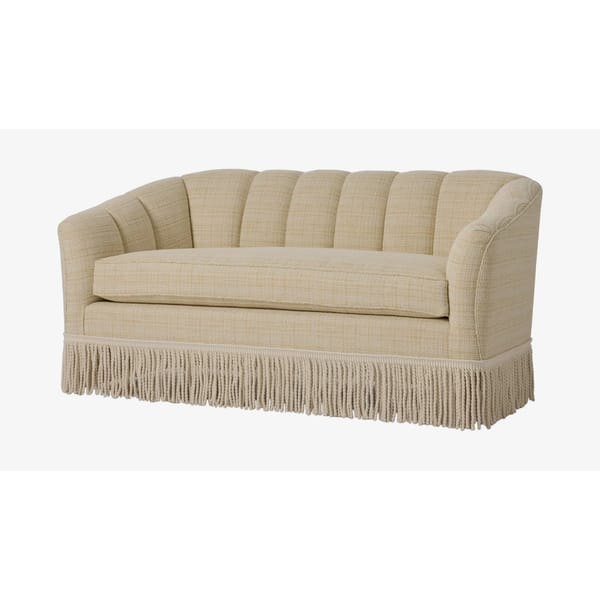 A beige upholstered two-seater sofa with a curved, scalloped back and single cushion, featuring decorative fringe along the bottom edge—a charming granny sofa perfect for adding vintage flair to your home decor.