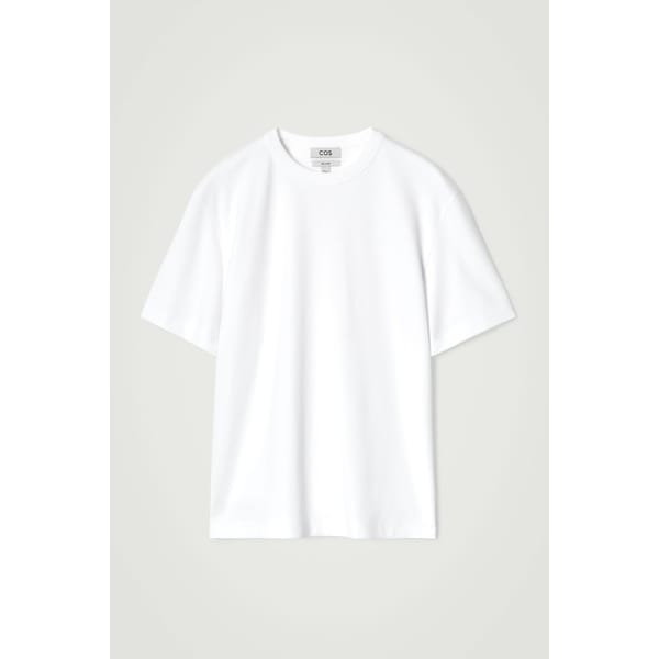 A plain white short-sleeve T-shirt with a crew neck, displayed against a light grey background. The relaxed fit makes it perfect for effortless layering—explore style tips for men to elevate this classic wardrobe staple. A small label is visible inside the collar.