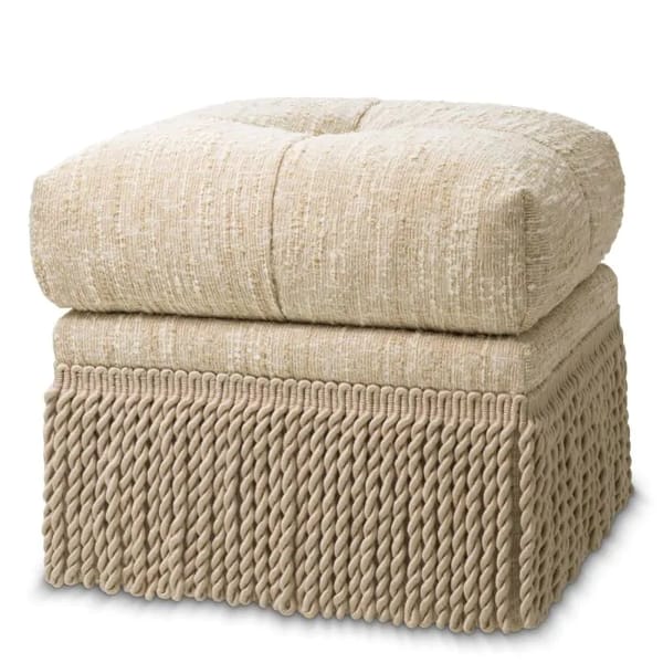 A square beige ottoman with a plush, tufted cushion top and a decorative, thick twisted rope fringe covering the bottom—perfect for adding vintage furniture charm to your living space.