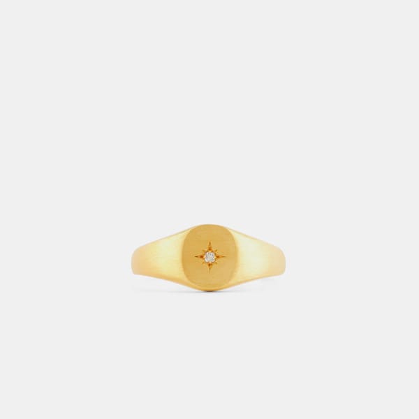 A gold signet ring with a brushed finish, featuring a small diamond set in the centre of an engraved starburst design—an elegant accessory and one of the best style tips for men seeking timeless sophistication.