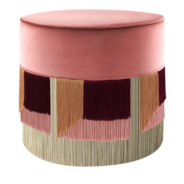 A round pouffe with a pink velvet top and multicoloured fringe in shades of burgundy, beige, and pink brings vintage charm—perfect for pairing with your favourite granny sofa.