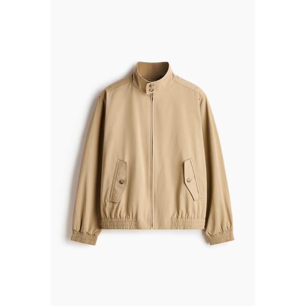A light brown, casual men's jacket with a stand-up collar, front zip, buttoned flap pockets, and elasticated cuffs and hem, displayed against a white background.