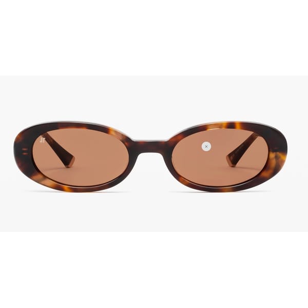 Oval tortoiseshell sunglasses with brown-tinted lenses, shown from the front against a white background. A small round sticker with an X is visible on the right lens—perfect for channelling cool '90s fashion in your '90s wardrobe.