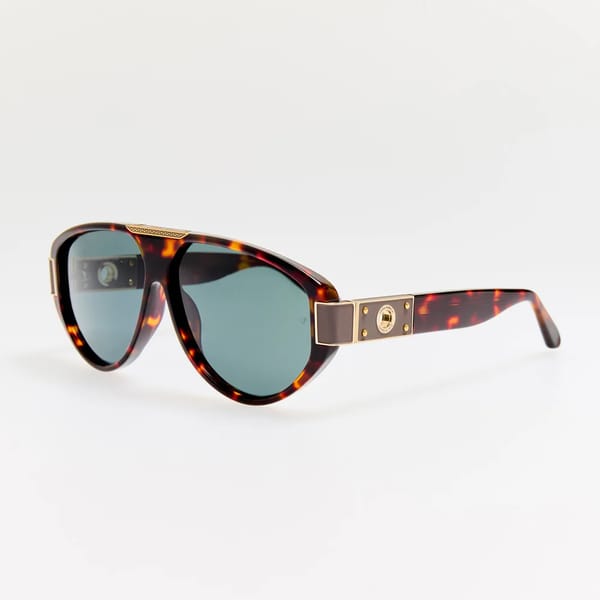 Tortoiseshell aviator-style sunglasses with blue tinted lenses, gold accents on the hinges, and a decorative gold plate on the temples, displayed on a white background.