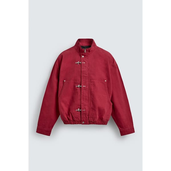 A maroon men's jacket with a high collar, front toggle fastenings, two side pockets, and an elasticated hem, displayed against a plain light grey background.